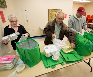 Photo of a group packing food. Links to Gifts of Real Estate