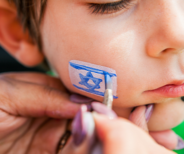 Photo of a boy getting the jewish flag painted on his cheek. Links to Gifts That Protect Your Assets